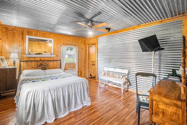 bedroom with ceiling fan, wooden walls, and hardwood / wood-style floors