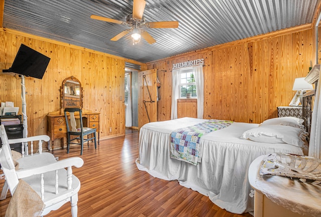 bedroom featuring ceiling fan, wooden walls, and wood-type flooring