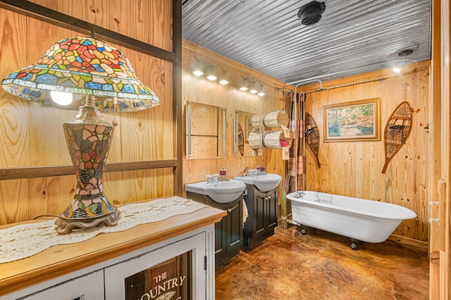 bathroom featuring wood walls, concrete floors, sink, and a bathing tub