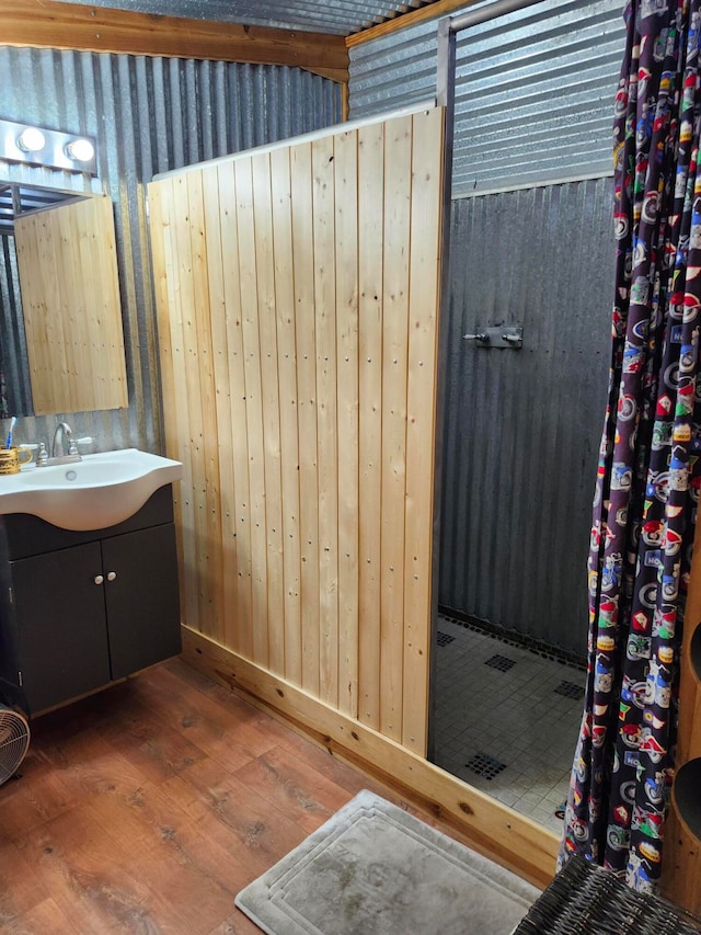 bathroom with a shower with curtain, wooden walls, vanity, and hardwood / wood-style floors