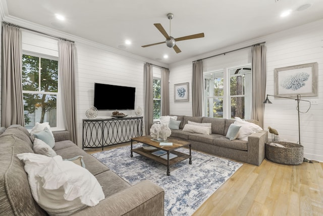 living room with hardwood / wood-style flooring, ornamental molding, and ceiling fan