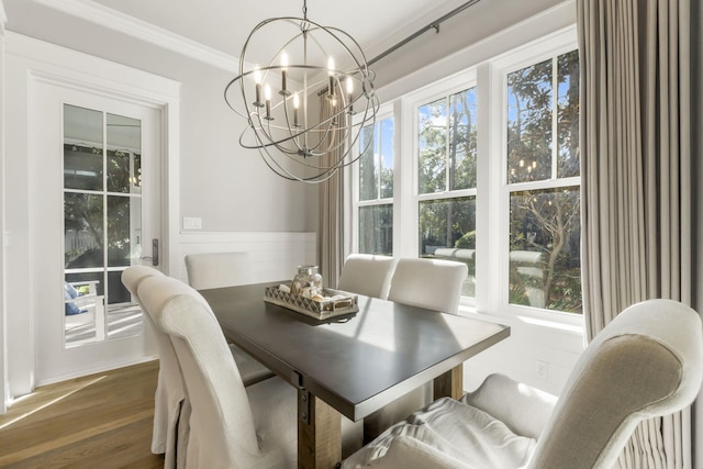 dining area with dark wood-type flooring, ornamental molding, a healthy amount of sunlight, and an inviting chandelier