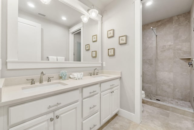 bathroom with vanity, toilet, and a tile shower