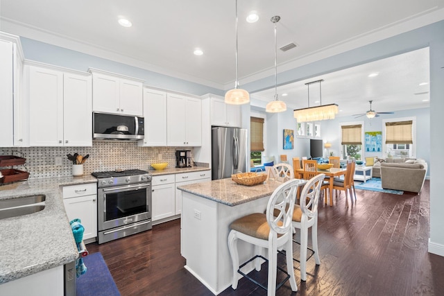 kitchen featuring sink, white cabinetry, stainless steel appliances, a center island, and light stone counters