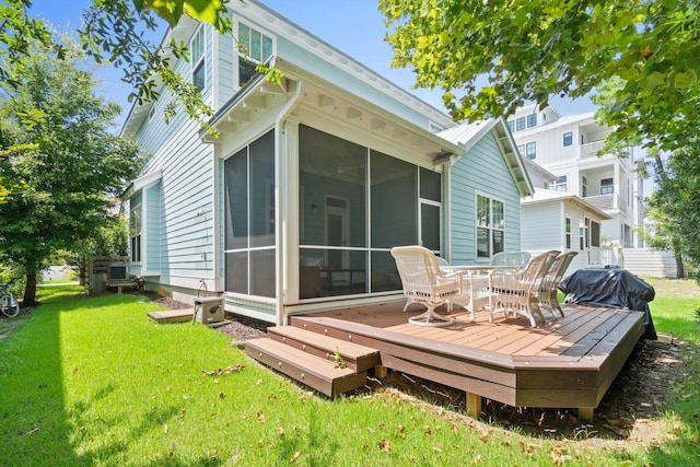 rear view of house with a wooden deck, a lawn, and a sunroom