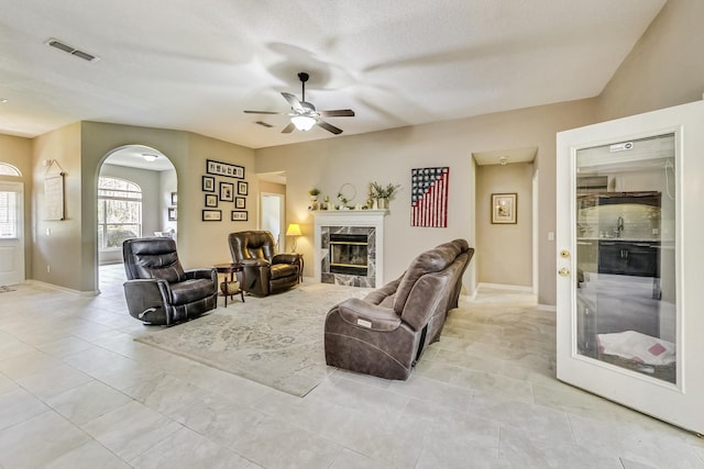 living room with a fireplace, ceiling fan, light tile patterned flooring, and sink