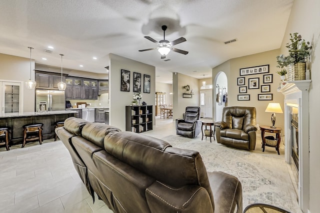 living room with a textured ceiling, ceiling fan, and light tile patterned floors