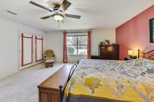 tiled bedroom with ceiling fan and a textured ceiling