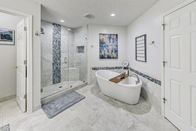 bathroom with separate shower and tub, a textured ceiling, tile patterned floors, and tile walls