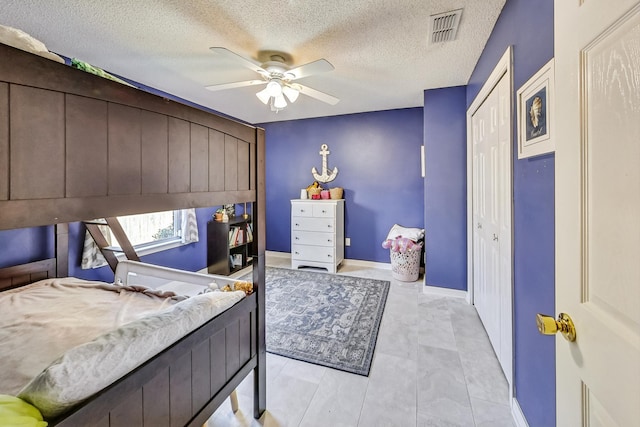 tiled bedroom with ceiling fan, a closet, and a textured ceiling