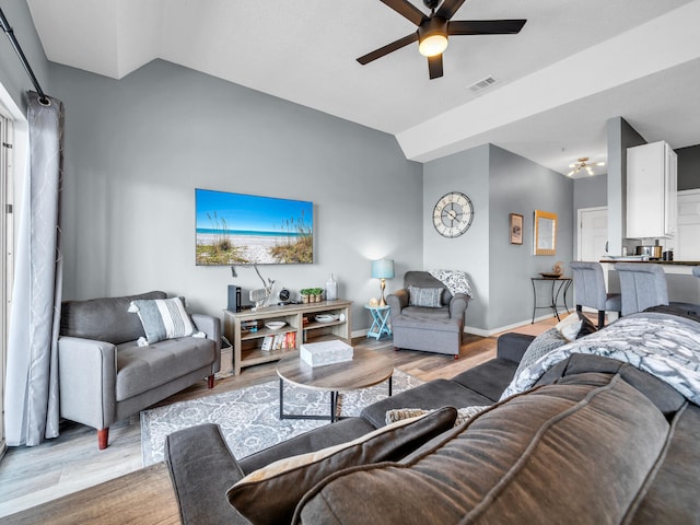 living area featuring visible vents, light wood-style floors, vaulted ceiling, baseboards, and a ceiling fan