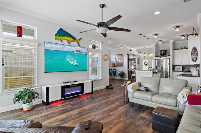 living room with crown molding, ceiling fan, plenty of natural light, and dark wood-type flooring