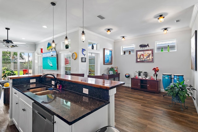 kitchen featuring an island with sink, sink, dark stone countertops, and white cabinets