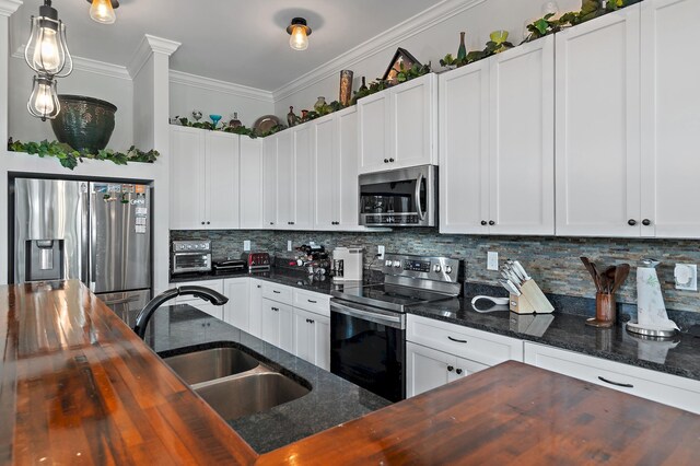 kitchen with butcher block countertops, tasteful backsplash, white cabinetry, appliances with stainless steel finishes, and sink