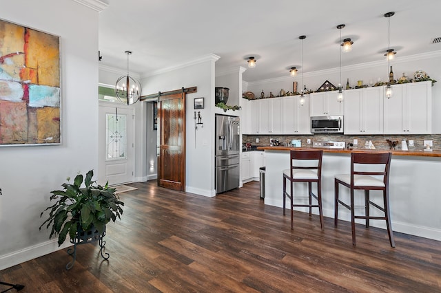 kitchen with appliances with stainless steel finishes, decorative light fixtures, dark hardwood / wood-style floors, and a barn door