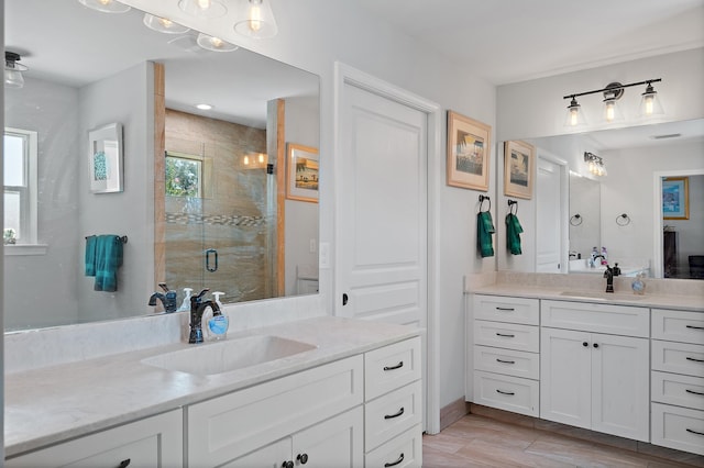 bathroom featuring a shower with door and dual vanity