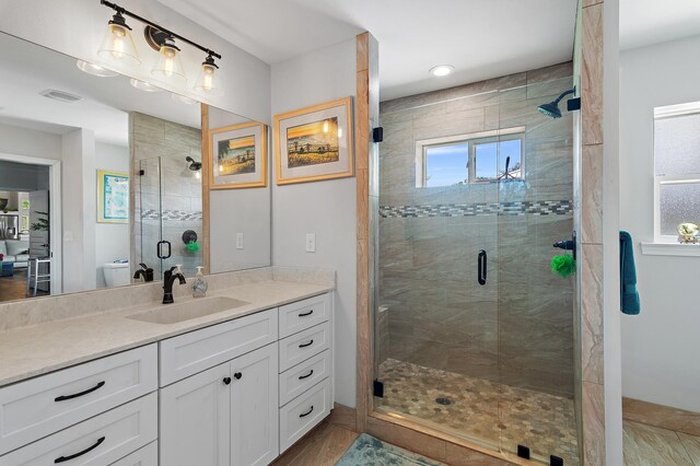 bathroom featuring tile patterned flooring, a shower with door, toilet, and vanity