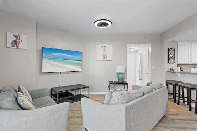 living area featuring baseboards and light wood finished floors