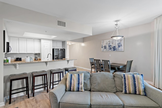 living room featuring light wood finished floors, baseboards, and visible vents