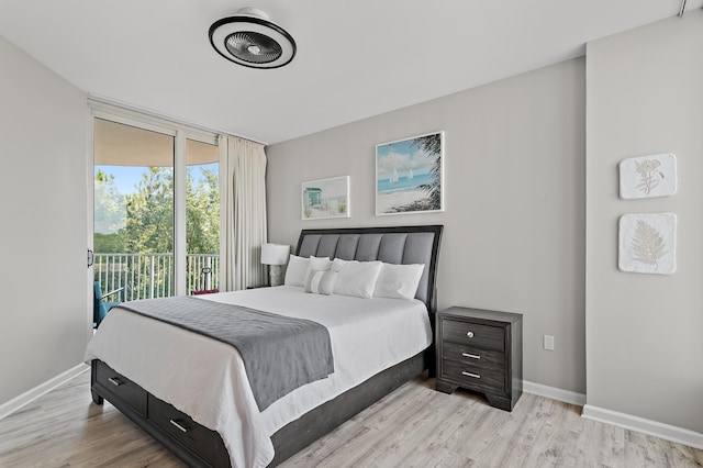 bedroom featuring access to exterior, light wood-type flooring, baseboards, and a wall of windows