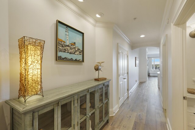 hallway with light wood-type flooring and ornamental molding