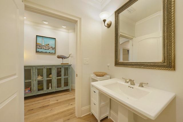 bathroom featuring hardwood / wood-style floors, crown molding, sink, and toilet