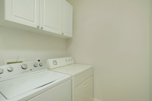 clothes washing area with washer and clothes dryer and cabinets