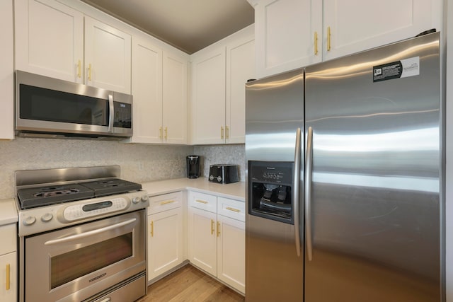 kitchen with appliances with stainless steel finishes, decorative backsplash, white cabinetry, and light hardwood / wood-style floors