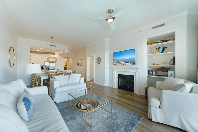 living room featuring ceiling fan, a premium fireplace, ornamental molding, and hardwood / wood-style floors