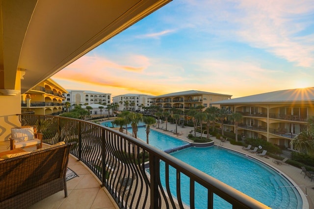 balcony at dusk featuring a community pool