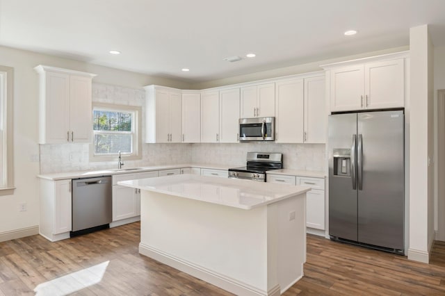 76 Azalea Dr, Freeport, FL 32439 - kitchen featuring appliances with stainless steel finishes, a sink, white cabinetry, backsplash, and wood finished floors