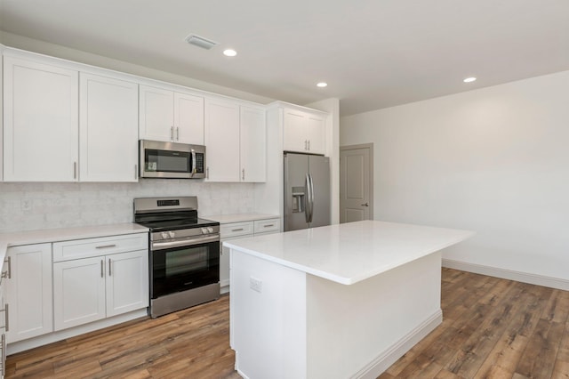 76 Azalea Dr, Freeport, FL 32439 - kitchen featuring stainless steel appliances, wood finished floors, tasteful backsplash, white cabinets, and a kitchen island