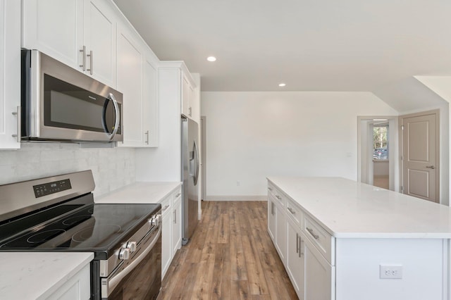 76 Azalea Dr, Freeport, FL 32439 - kitchen with appliances with stainless steel finishes, a kitchen island, decorative backsplash, light wood finished floors, and white cabinetry