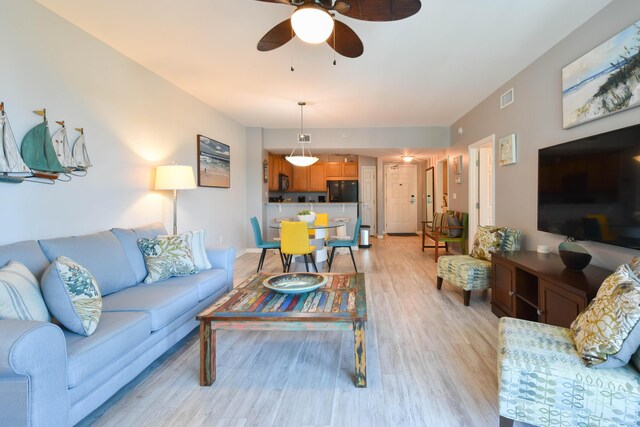 living room with ceiling fan and light hardwood / wood-style flooring