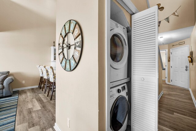 clothes washing area with hardwood / wood-style floors and stacked washer and clothes dryer