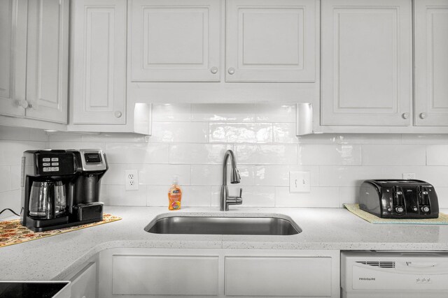 kitchen with white cabinets, tasteful backsplash, sink, and dishwasher