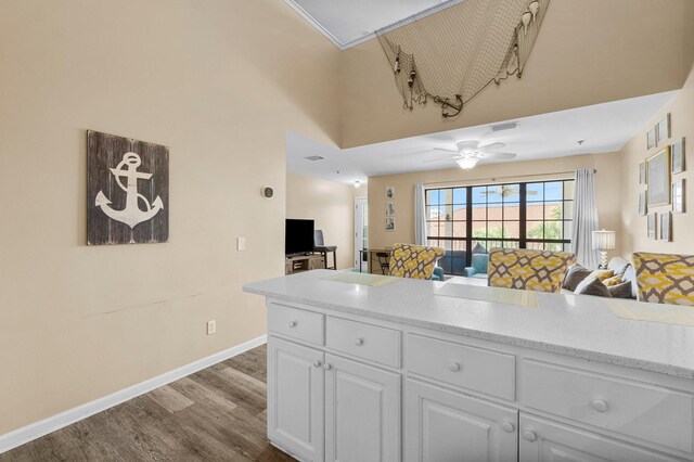 kitchen featuring white cabinets, light hardwood / wood-style floors, a towering ceiling, and ceiling fan