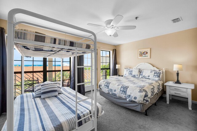 bedroom with carpet, a water view, and ceiling fan