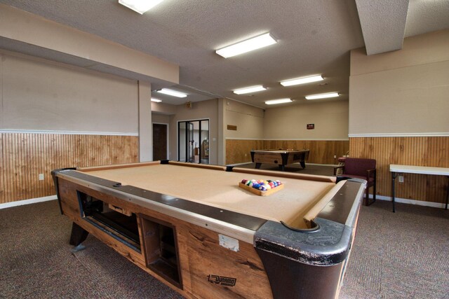 recreation room featuring a textured ceiling, pool table, and dark colored carpet