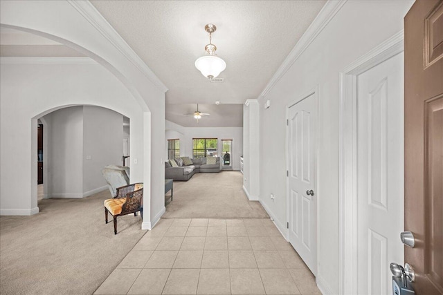 hallway with light tile patterned flooring, a textured ceiling, and crown molding