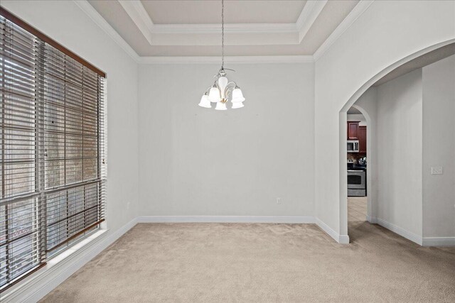 carpeted empty room with a raised ceiling, ornamental molding, and an inviting chandelier