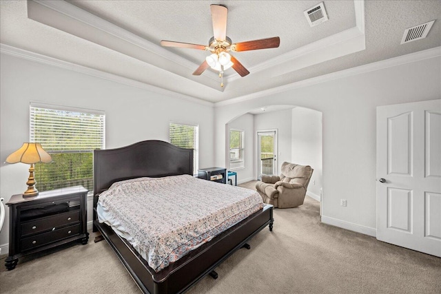 carpeted bedroom with ceiling fan, a textured ceiling, ornamental molding, and a tray ceiling