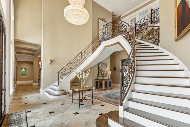 foyer entrance featuring light tile patterned floors, crown molding, a high ceiling, and a notable chandelier