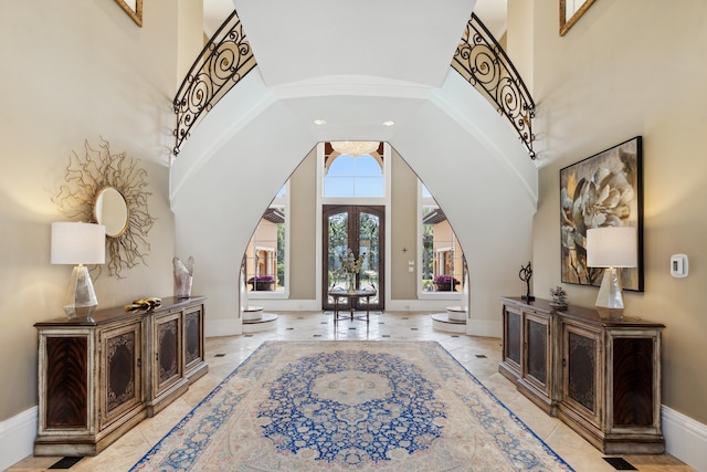 tiled foyer with a towering ceiling and french doors