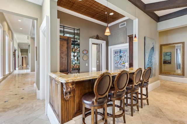 bar with decorative light fixtures, ornamental molding, light tile patterned floors, and light stone counters