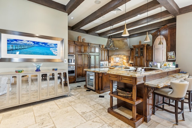 kitchen featuring a center island, pendant lighting, beam ceiling, and light stone countertops