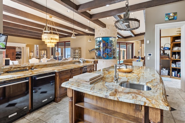 kitchen featuring beam ceiling, a sink, open floor plan, an inviting chandelier, and stone tile floors