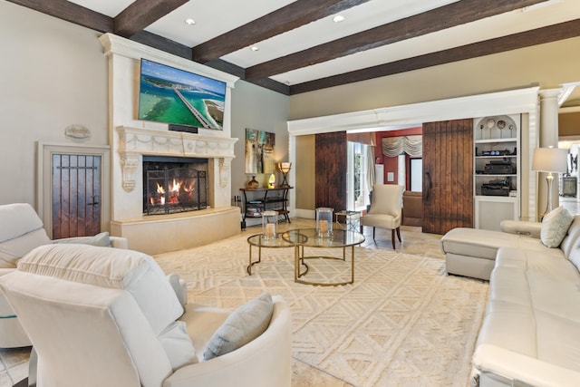 living room featuring a fireplace, beam ceiling, built in features, and ornate columns