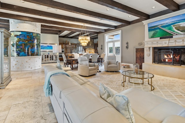 living area with an inviting chandelier, stone tile flooring, beamed ceiling, and a fireplace