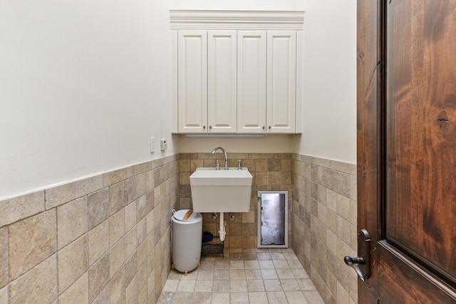 interior space featuring light tile patterned floors, sink, and tile walls